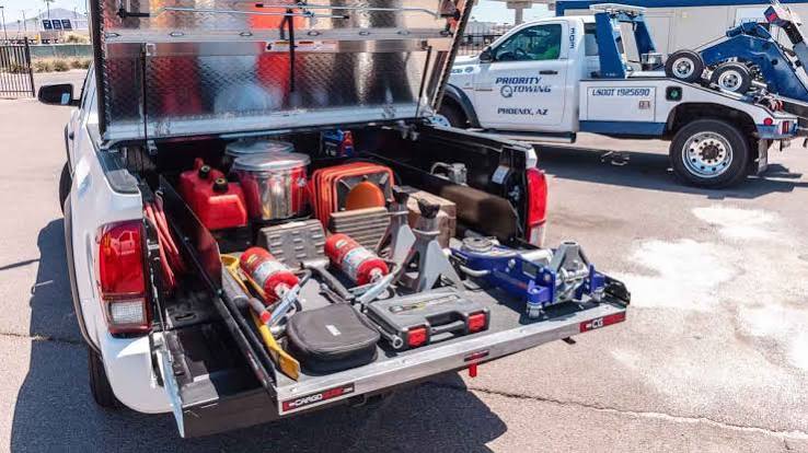 Service truck bed loaded with roadside assistance jacks, tools and fuel cans